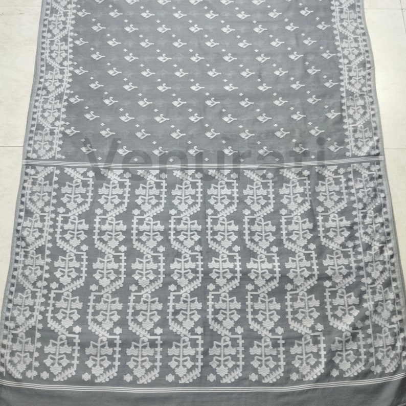 May include: A gray and white cotton saree with a floral pattern. The saree has a white border with a geometric design.