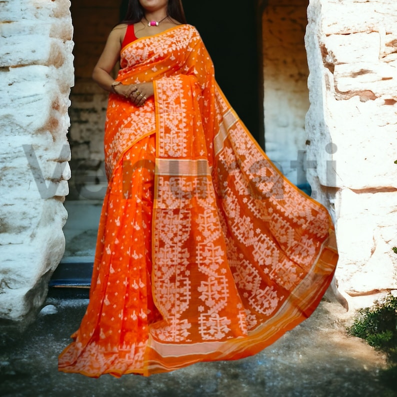 May include: A bright orange and white saree with a traditional Indian design. The saree is made of a lightweight fabric and has a flowing silhouette.
