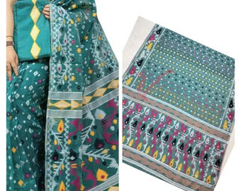 May include: A teal blue saree with white, yellow, pink, and black floral and geometric patterns. The saree has a white border with a yellow and white diamond pattern.