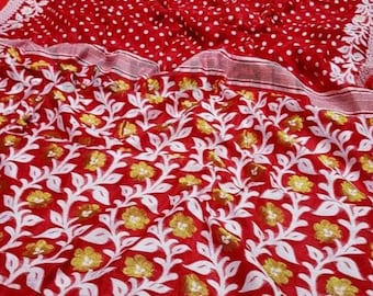 May include: Red and white saree with a white floral pattern and red polka dots.