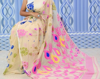 May include: A sheer white saree with pink, yellow, and blue floral patterns. The saree is draped around a person and has a white blouse underneath.