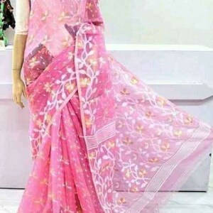 May include: A pink sheer saree with white floral embroidery. The saree is draped on a person and has a white border.