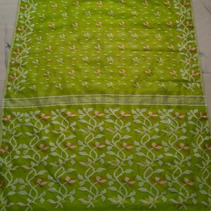 May include: A green and white saree with a floral pattern. The saree has a light green base with white and orange floral designs.