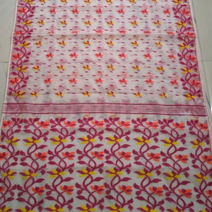 May include: White saree with a pink and orange floral pattern. The saree has a white border with a pink and orange floral design.