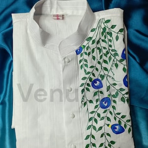 May include: White long-sleeved shirt with a mandarin collar and a hand-painted design of blue flowers and green leaves on the right side. The shirt has a label that says "girl".