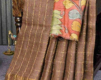 May include: A brown and gold checkered saree with a floral patterned pallu. The saree is draped over a wooden stool.