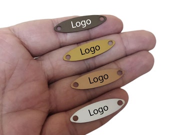 May include: Four oval-shaped metal tags with holes for attaching to items. Each tag is a different color: brown, gold, light brown, and silver. The word "Logo" is printed in black on each tag.