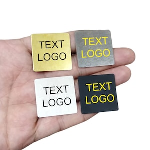 May include: Four square metal tags with rounded corners. The tags are in gold, silver, white, and black. Each tag has the text "TEXT LOGO" printed on it in yellow or black.