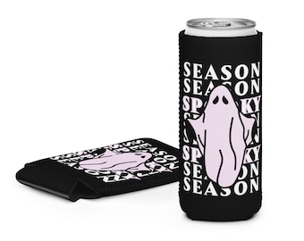 Puede incluir: Enfriador de latas negro con un gráfico de fantasma morado claro y las palabras "Spooky Season" en blanco. También se ve un segundo enfriador plegado. El diseño se repite en ambos enfriadores.