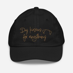 May include: Black baseball cap with the text "Dog kisses fix anything" embroidered in gold.