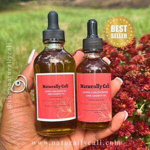 K&ouml;nnte beinhalten: Zwei Glasflaschen Naturally Cali Super Concentrated Hair Growth Oil mit schwarzen Tropfern und roten Etiketten. Die Etiketten enthalten den Text "Nettle & Mint Blend" und "Best Seller" in einem goldenen Stern. Die Flaschen werden in einer Hand gehalten.