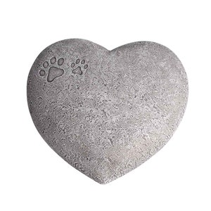 May include: A grey heart-shaped stone memorial with two paw prints etched into the surface.