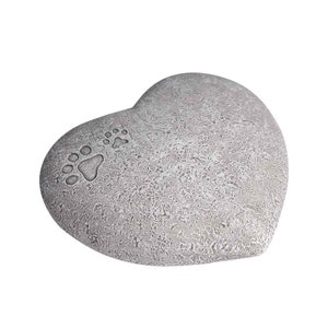 May include: A grey heart-shaped stone memorial with paw prints. The stone is textured and has a rustic look.