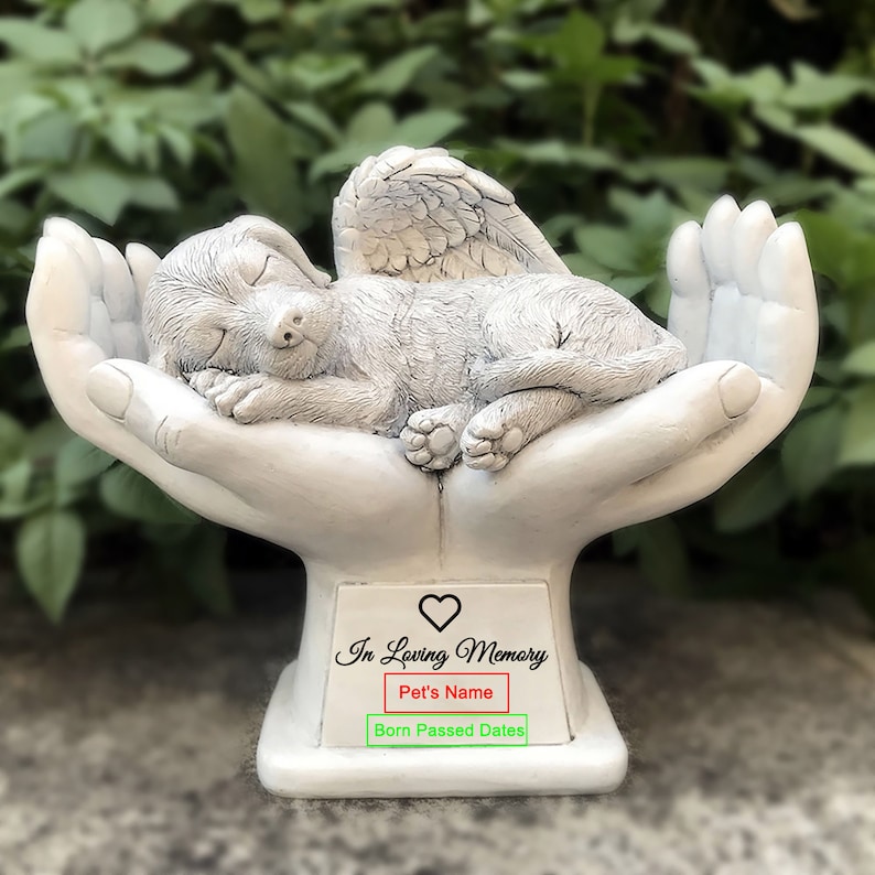 May include: White ceramic memorial statue of a sleeping angel dog with wings, resting in cupped hands. The base has the inscription "In Loving Memory" with space for a pet's name and birth and passing dates.