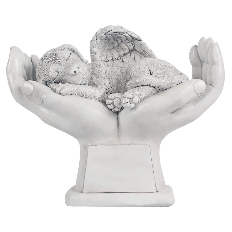 May include: White ceramic memorial sculpture of a sleeping angel dog with wings resting in cupped hands. The sculpture has a blank plaque for personalization.
