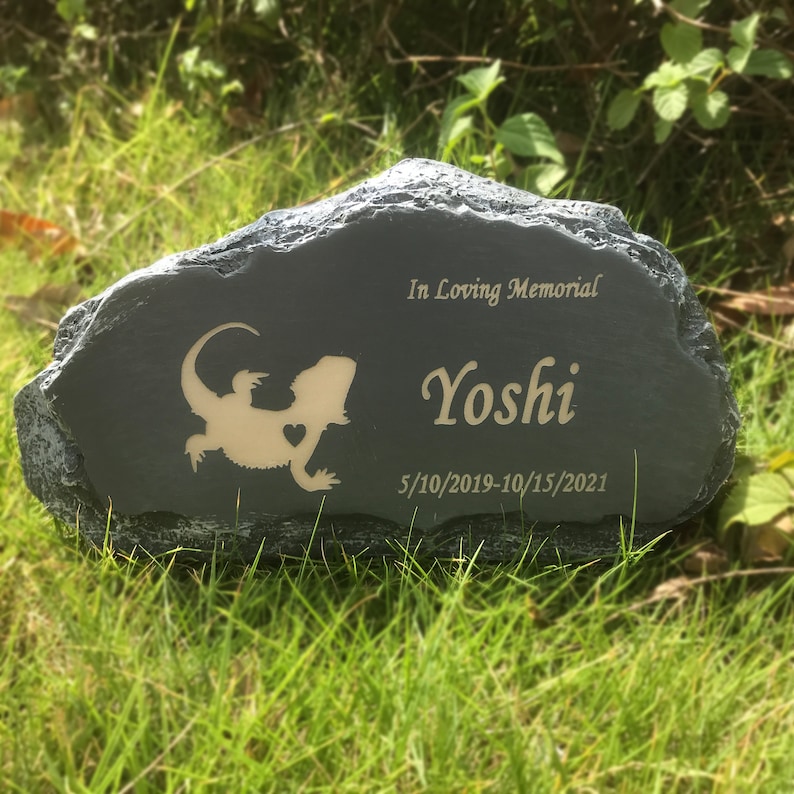 K&ouml;nnte beinhalten: Ein grauer Steindenkmal mit einer Eidechsen-Silhouette und der Inschrift "In Loving Memorial Yoshi 5/10/2019-10/15/2021".