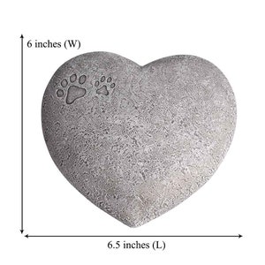 May include: A grey heart-shaped stone memorial with two paw prints. The stone measures 6.5 inches long and 6 inches wide.