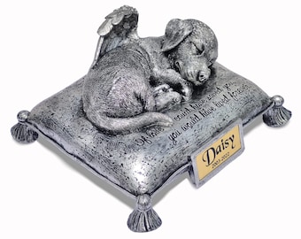 May include: Silver-colored pet memorial with a sleeping dog figurine with wings on a pillow. The pillow has the inscription "Of love could have saved you, you would have lived forever."  A gold plaque on the front reads "Daisy 2003-2022".