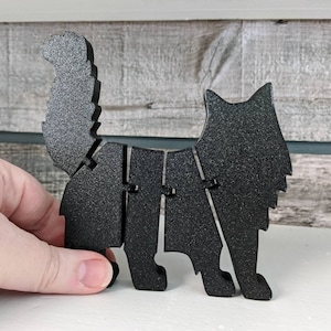 May include: Black cat figurine made of wood. The cat is standing on all four legs with its tail curled up behind it. The figurine is painted black and has a textured surface.