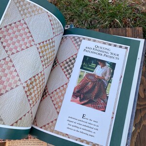 Pode incluir: Um livro aberto em uma p&aacute;gina sobre quilting e acabamento de projetos de patchwork. A p&aacute;gina apresenta uma foto de uma mulher acolchoando um edredom de patchwork com uma variedade de cores e padr&otilde;es. O texto na p&aacute;gina diz "Mesmo o patchwork mais simples adquire um ar elegante quando embelezado com quilting ou bordado finos, como mostrado nas p&aacute;ginas seguintes."