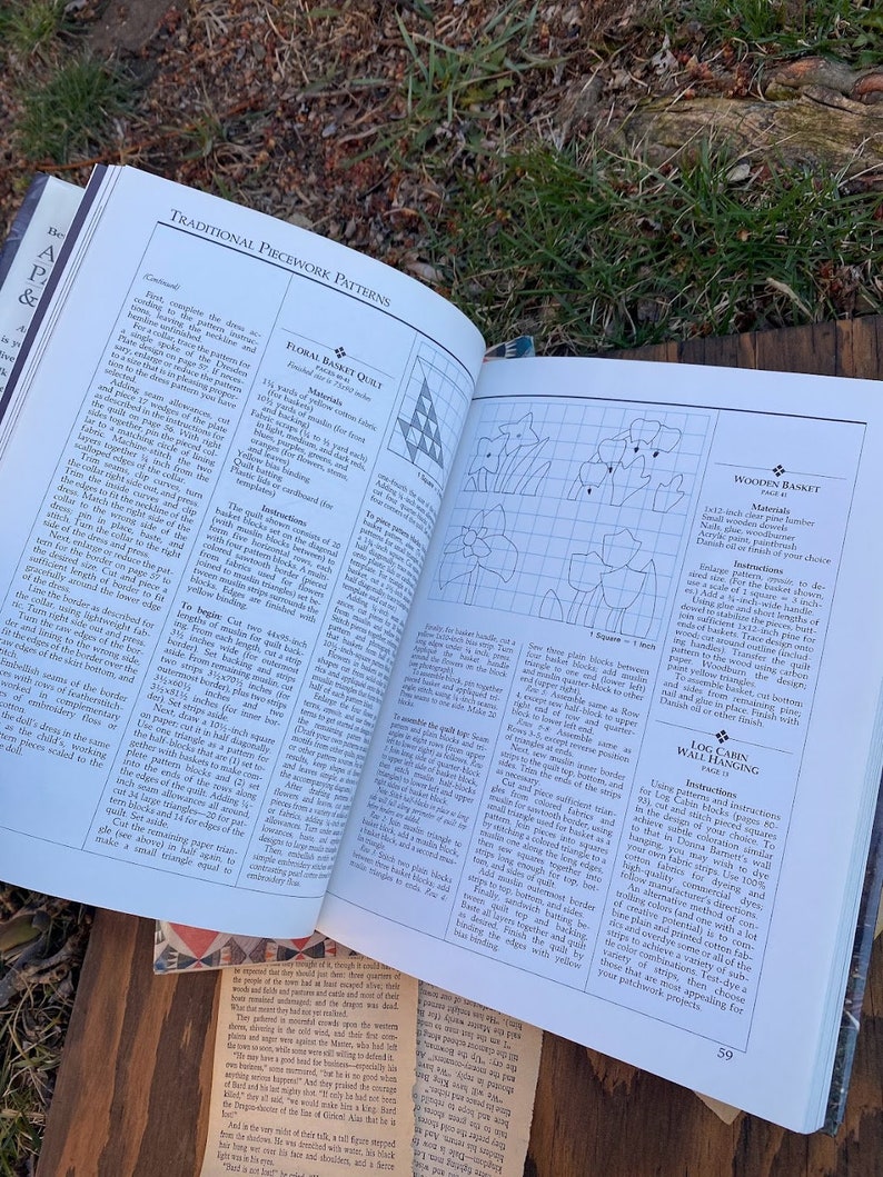Pode incluir: Um livro aberto numa p&aacute;gina com instru&ccedil;&otilde;es para fazer um quilt de cesta floral, uma cesta de madeira e uma parede de cabana de troncos. O livro apresenta ilustra&ccedil;&otilde;es de cada projeto e lista os materiais necess&aacute;rios.