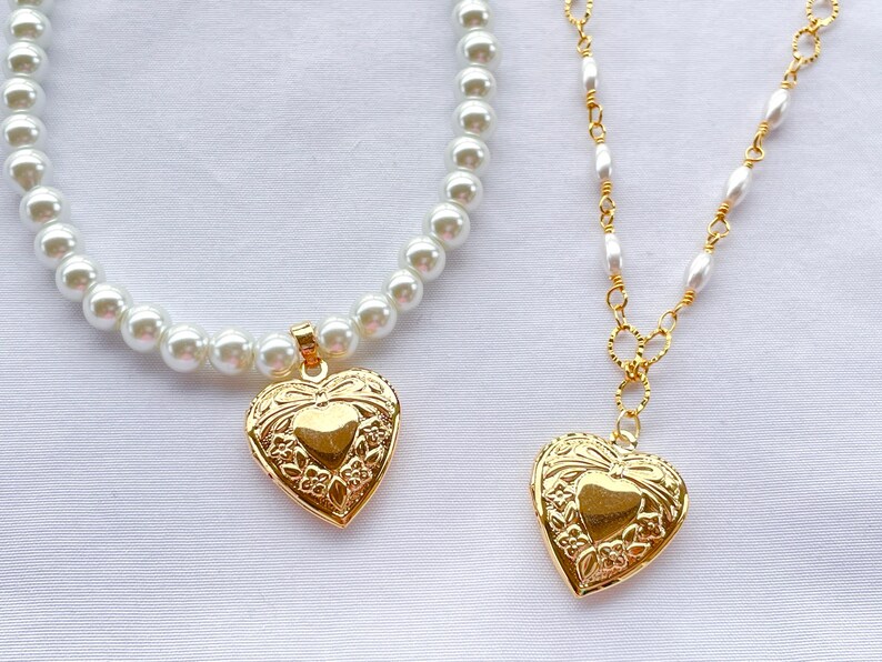 May include: Two gold heart-shaped lockets on necklaces. One necklace is a pearl strand and the other is a gold chain with pearl accents.