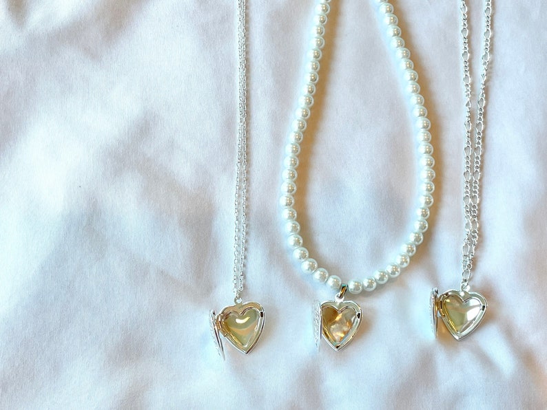 Peut inclure: Trois colliers en argent avec des pendentifs en forme de c&oelig;ur. Le collier de gauche a une cha&icirc;ne d&eacute;licate, le collier du milieu a une cha&icirc;ne de perles et le collier de droite a une cha&icirc;ne plus &eacute;paisse.