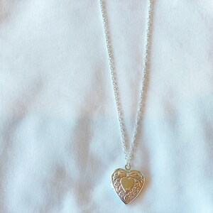 Peut inclure: Un collier avec un pendentif en forme de c&oelig;ur argent&eacute; orn&eacute;. Le pendentif a une petite ouverture en forme de c&oelig;ur au centre.
