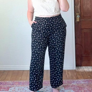 May include: Black and white floral print pants with a wide leg silhouette. The pants have a high waist and a relaxed fit.