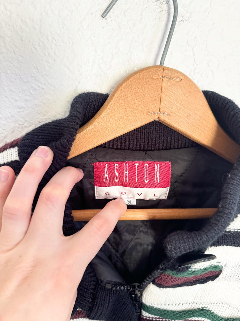 Peut inclure: Pullover ray&eacute; noir et blanc avec une &eacute;tiquette rouge et blanche indiquant "Ashton Cove" et une taille "M".