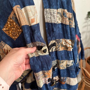 Puede incluir: Chaqueta patchwork en tonos azules, beige y marr&oacute;n. La chaqueta presenta una variedad de cuadrados de tela estampada cosidos. Tiene cierre de botones y un ajuste relajado, adecuado para superponer. El dise&ntilde;o de la chaqueta recuerda a los estilos vintage o bohemios.