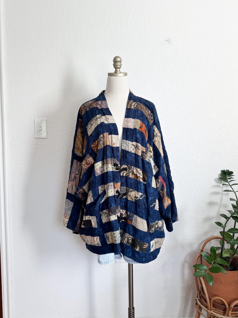 Puede incluir: Una chaqueta azul marino de frente abierto con un dise&ntilde;o de patchwork. La chaqueta presenta rayas horizontales de varias telas estampadas en tonos beige, marr&oacute;n y naranja. La chaqueta se exhibe en un maniqu&iacute;.