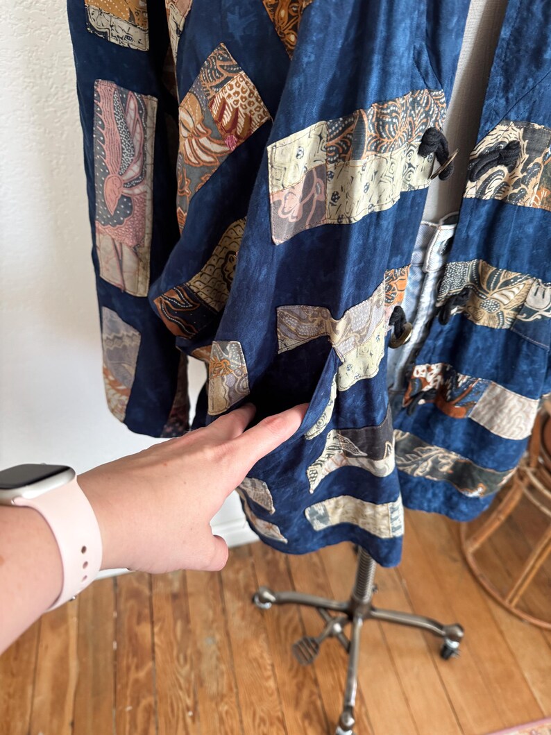 Puede incluir: Chaqueta patchwork azul marino con parches rectangulares y en forma de diamante. Los parches presentan varios patrones en beige, marr&oacute;n y rosa. La chaqueta tiene un bolsillo y cierres de palanca negros.