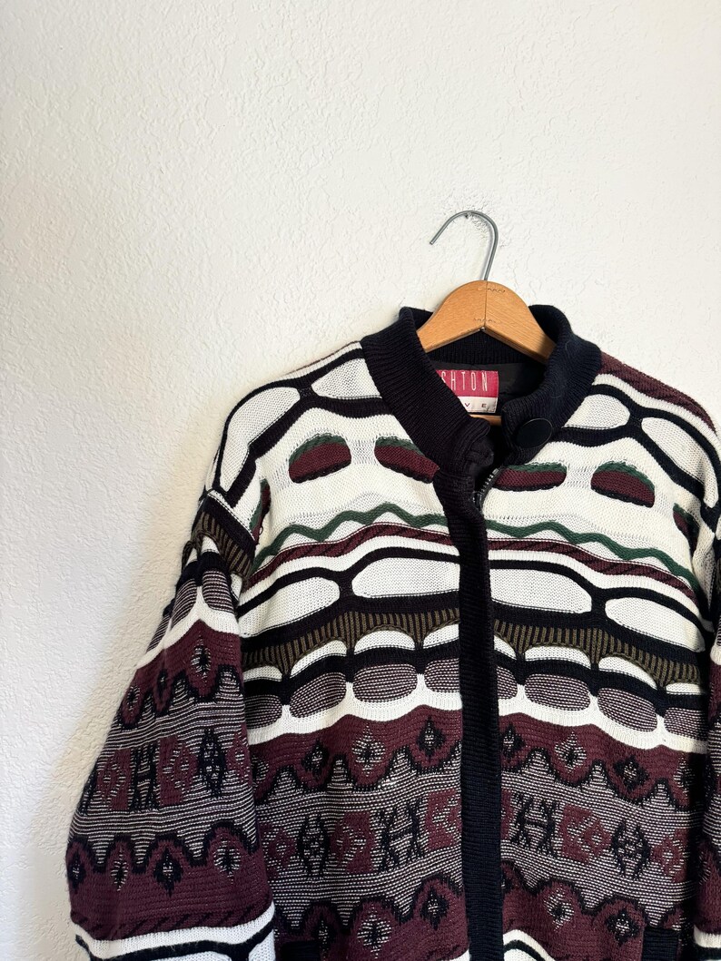 Peut inclure: Un cardigan zipp&eacute; &agrave; motif noir, blanc, marron et vert avec l'inscription "Brighton" sur l'&eacute;tiquette.