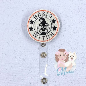 May include: A round badge with the words "BASIC WITCH" encircling a witch illustration. The badge is white with black text and a red border. The badge is attached to a clear plastic retractable badge holder.