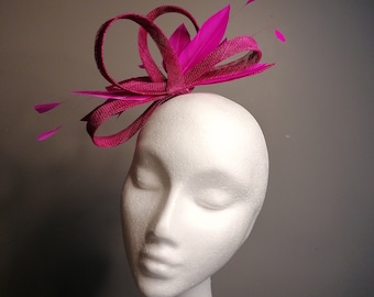 May include: A fuchsia pink feather and ribbon hair comb. The comb is made of a thin, flexible material and has a small, delicate design.