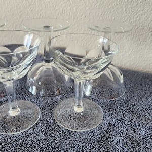 May include: Set of four clear glass stemmed cocktail glasses with a cut glass design.