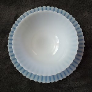 Pu&ograve; includere: Una ciotola in vetro di latte bianco con un bordo smerlato blu e bianco. La ciotola &egrave; vuota e si trova su una superficie grigio scuro.