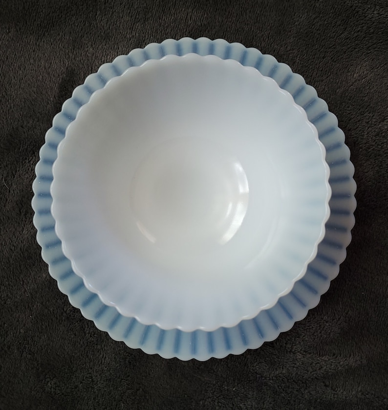 Pu&ograve; includere: Una ciotola in vetro di latte bianco con un bordo smerlato blu e bianco. La ciotola &egrave; vuota e si trova su una superficie grigio scuro.
