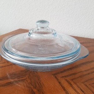 May include: A vintage light blue glass baking dish with a lid. The dish has a scalloped edge and a floral design.