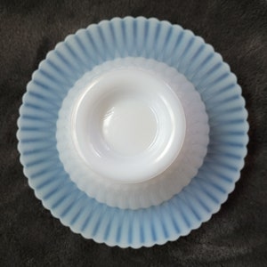 Pu&ograve; includere: Una ciotola in vetro di latte bianco con un bordo smerlato blu e bianco si trova su un piattino smerlato blu e bianco abbinato.
