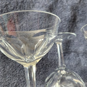 May include: A set of four clear glass wine glasses with a decorative etched pattern. The glasses are stacked on top of each other.