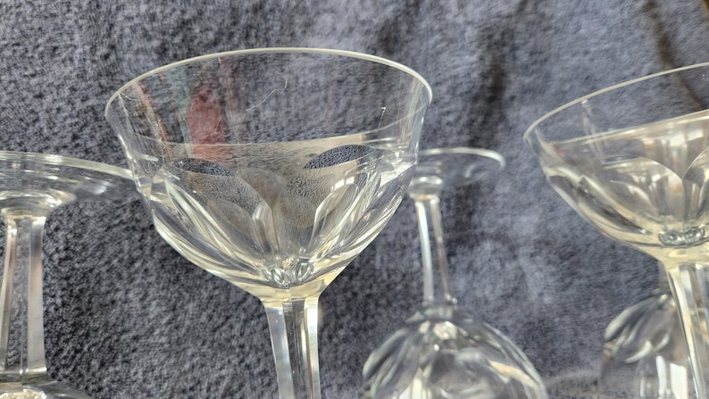 May include: A set of four clear glass wine glasses with a decorative etched pattern. The glasses are stacked on top of each other.