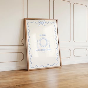 May include: A framed print with a white background and blue text that reads "NO GUNS AT THE DINNER TABLE." The print features a blue illustration of a plate, fork, knife, and spoon.