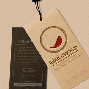 May include: A brown paper label mockup featuring a red chilli pepper graphic and the text "label mockup" in a white font. The text below the graphic reads "High Resolution Label PSD Mockups with Smartobject". The website address "www.zippypixels.com" is printed at the bottom of the label.