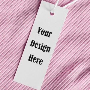 May include: White tag with black text that reads "Your Design Here" on a pink ribbed fabric background.