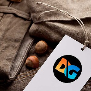 May include: A white tag with a black circle containing the letters "DG" in orange, blue, and white. The tag is attached to a brown fabric with a string.