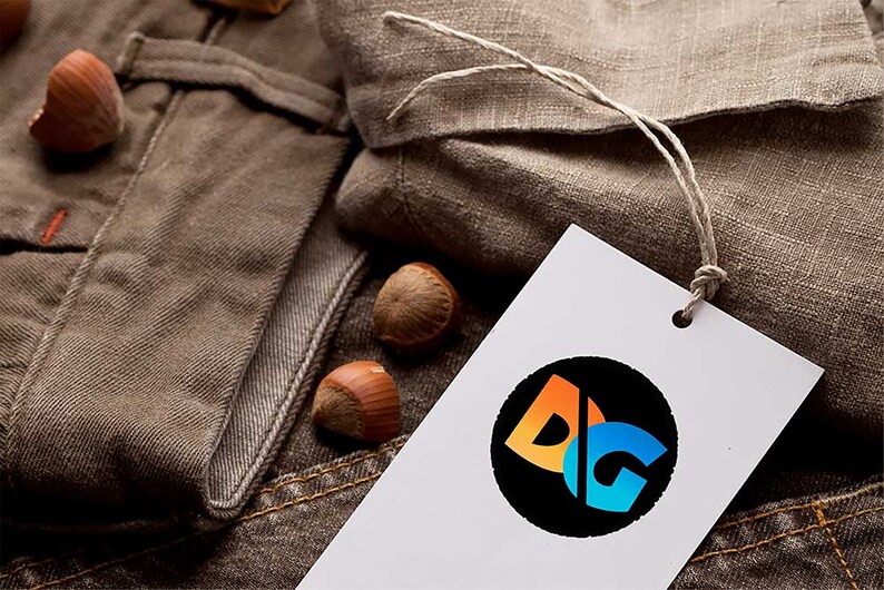 May include: A white tag with a black circle containing the letters "DG" in orange, blue, and white. The tag is attached to a brown fabric with a string.