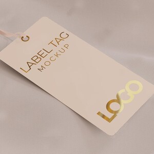 May include: A blank beige label tag with a gold foil inscription that reads "LABEL TAG MOCKUP" and a gold foil logo that reads "LOGO".