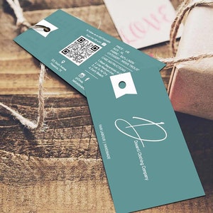 May include: A teal blue tag with white text and a QR code. The tag says "Dovanti Clothing Company", "Fair Labour Handmade", "Price: $15", "Size: XL", "Fabric: 100% Linen", "Category: Men's Trousers", and includes care instructions.